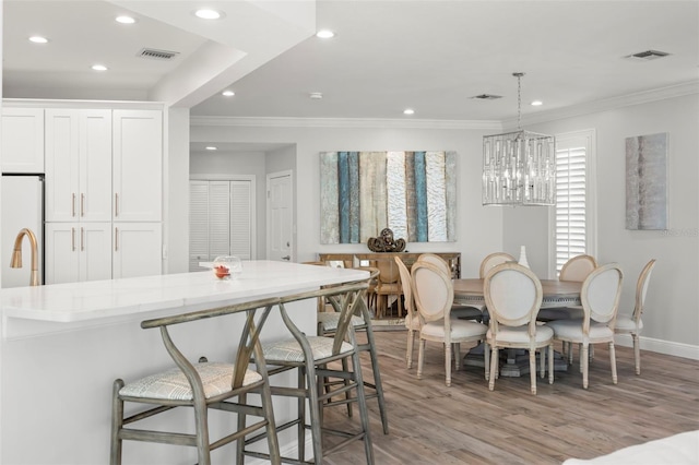 dining room featuring a notable chandelier, light wood-type flooring, and crown molding