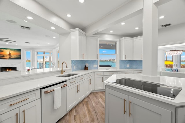 kitchen with dishwasher, sink, black electric cooktop, a fireplace, and white cabinets