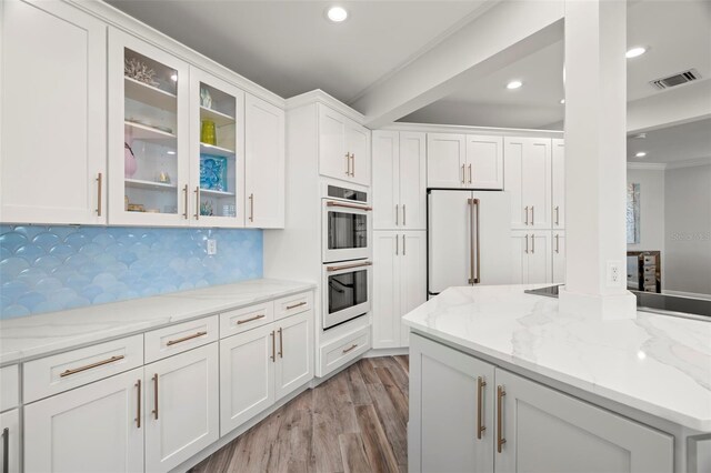 kitchen with white cabinets, decorative backsplash, high end fridge, and light stone countertops