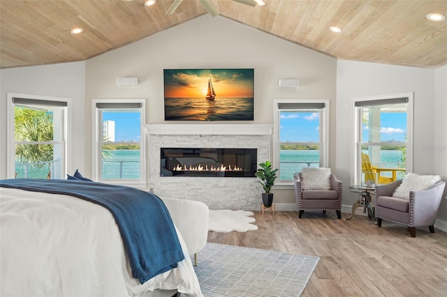 bedroom with vaulted ceiling, wood ceiling, a fireplace, and light hardwood / wood-style flooring