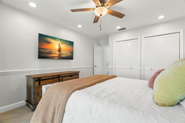 bedroom featuring carpet, ceiling fan, and multiple closets