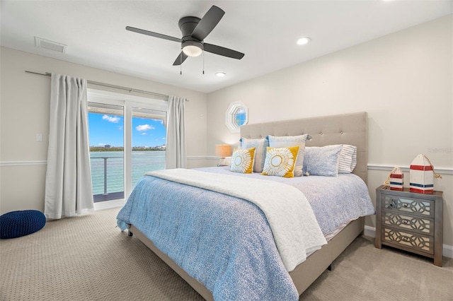 bedroom featuring access to exterior, light carpet, a water view, and ceiling fan