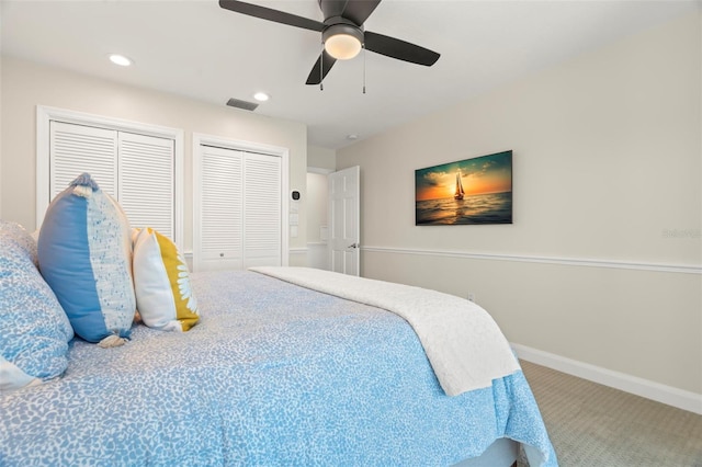 bedroom with ceiling fan, carpet floors, and multiple closets