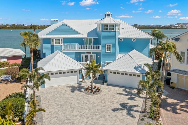 coastal inspired home with a balcony, a garage, and a water view