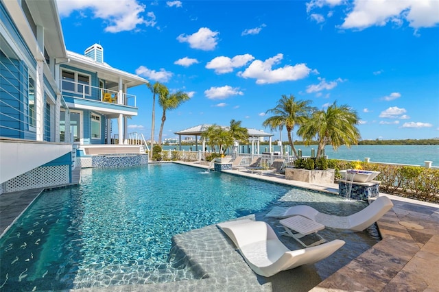 view of pool featuring pool water feature, a water view, and a patio area