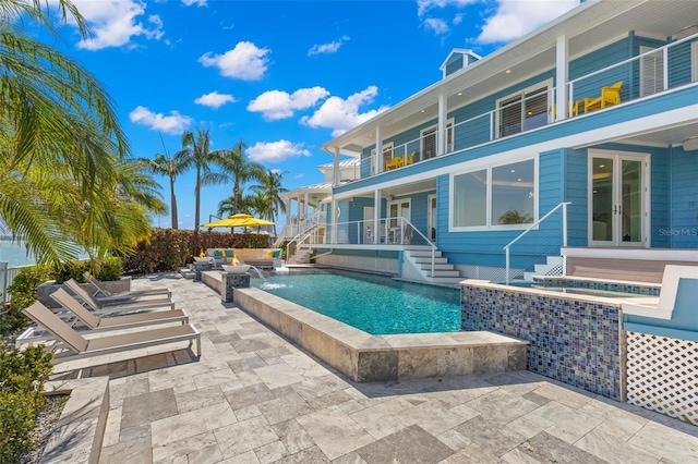 view of pool featuring pool water feature, french doors, a patio, and a hot tub