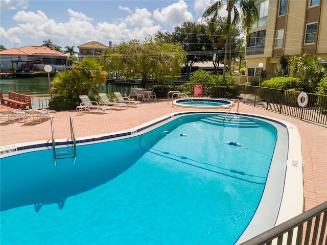 view of pool featuring a water view, a patio, and a hot tub