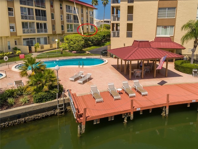 view of swimming pool with a gazebo, a patio, a water view, and a dock