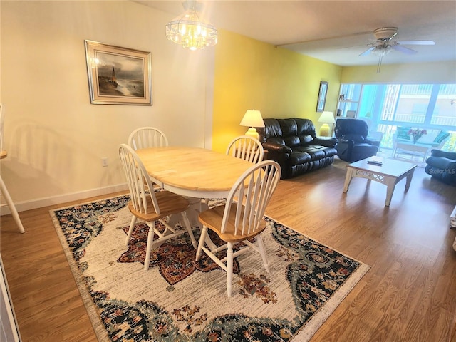 dining area featuring wood-type flooring and ceiling fan with notable chandelier