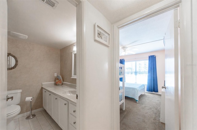 bathroom featuring ceiling fan, tile patterned floors, a textured ceiling, toilet, and vanity