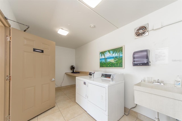 clothes washing area with washer and clothes dryer, light tile patterned floors, and sink