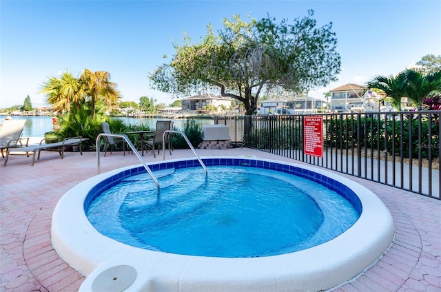 view of pool featuring a water view and a hot tub