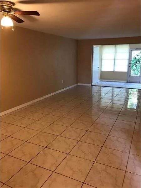 tiled spare room with ceiling fan