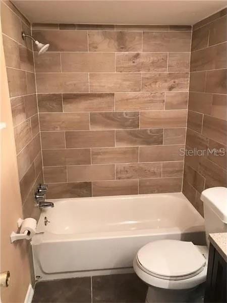 full bathroom featuring tiled shower / bath combo, vanity, and toilet