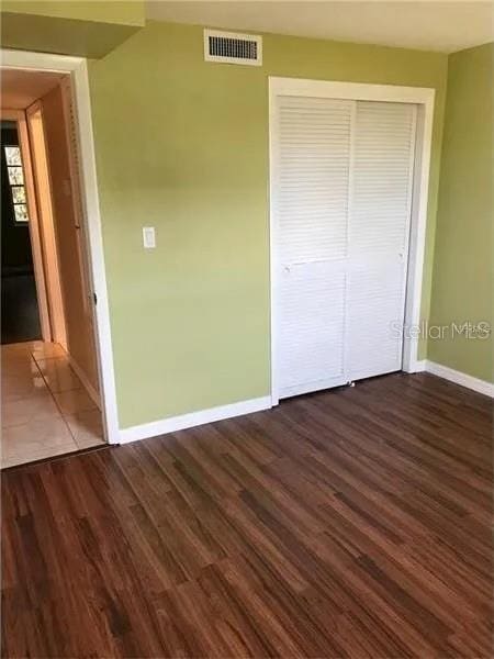 unfurnished bedroom featuring a closet and dark wood-type flooring