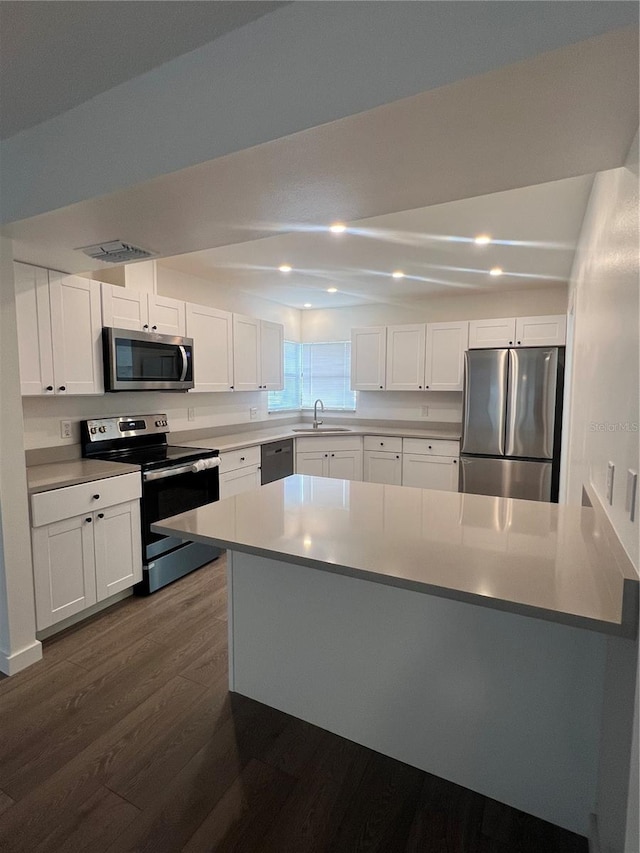 kitchen with white cabinets, dark wood-type flooring, appliances with stainless steel finishes, and sink