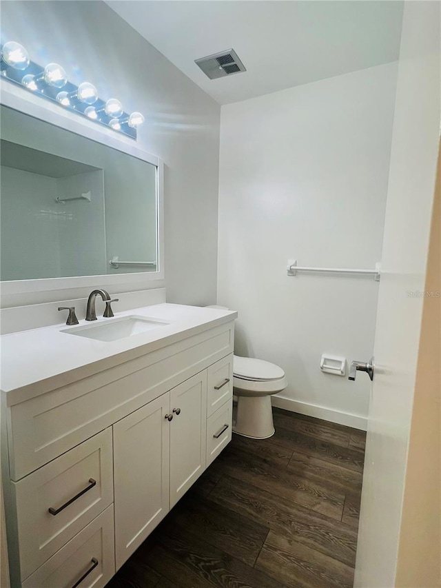 bathroom with toilet, vanity, and wood-type flooring