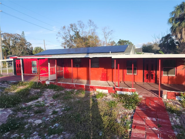 back of property with solar panels and a patio