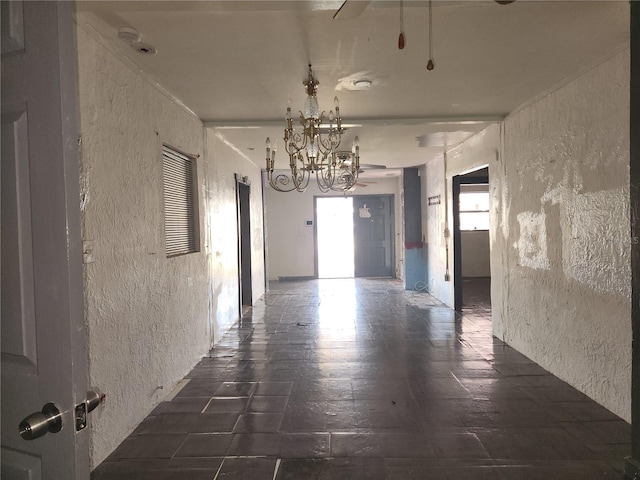 corridor with dark tile flooring and a notable chandelier