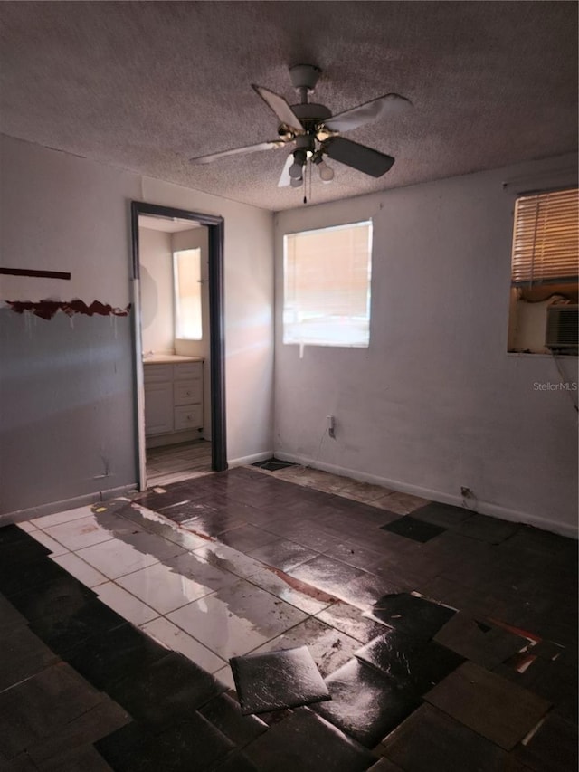 unfurnished bedroom with ensuite bathroom, dark tile floors, ceiling fan, and a textured ceiling