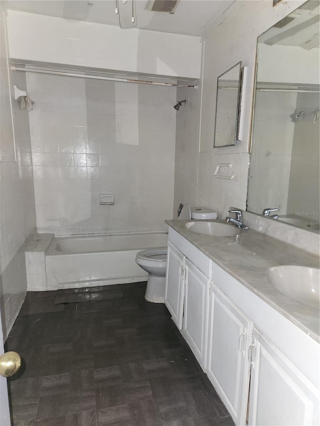 full bathroom featuring tiled shower / bath, toilet, dual bowl vanity, and parquet floors