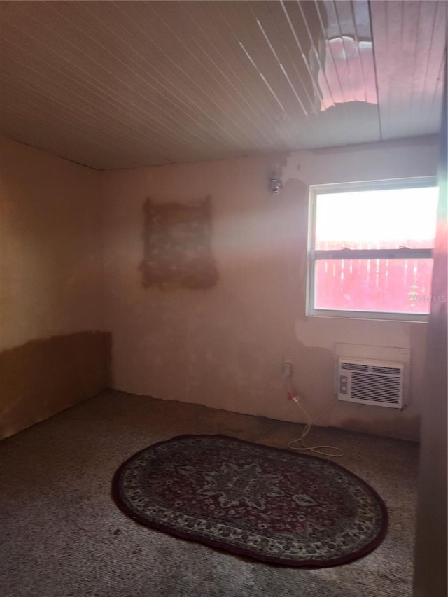 carpeted spare room featuring a wall mounted AC and wood ceiling