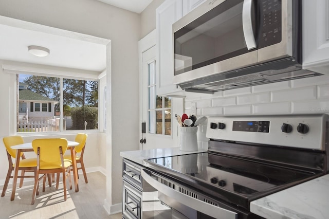 kitchen featuring white cabinetry, light stone countertops, light hardwood / wood-style flooring, and stainless steel appliances