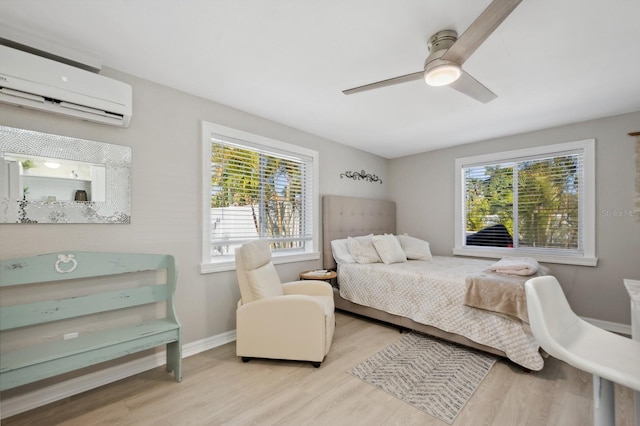 bedroom with a wall mounted air conditioner, light wood-type flooring, and ceiling fan