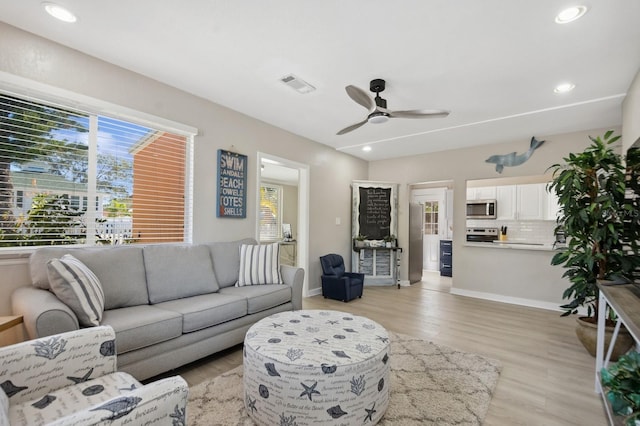 living room with a wealth of natural light, ceiling fan, and light hardwood / wood-style flooring