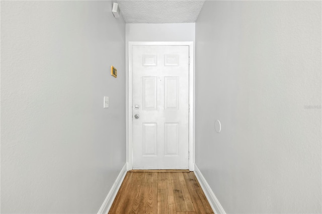 hallway with a textured ceiling and light wood-type flooring