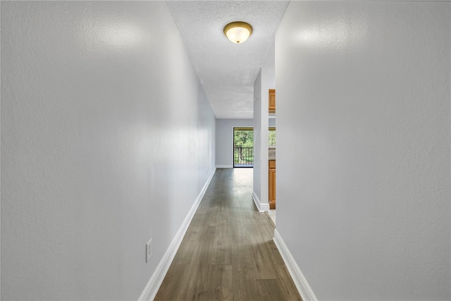 hallway with a textured ceiling and dark wood-type flooring