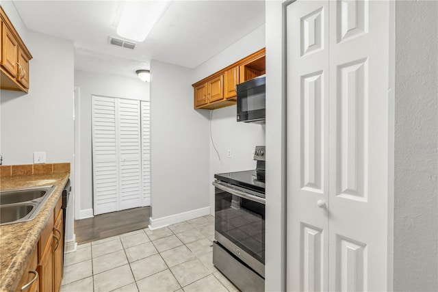 kitchen with sink, stainless steel electric stove, and light tile flooring