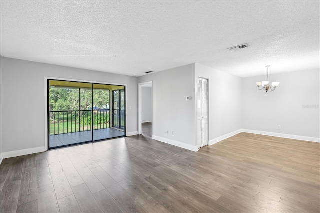 empty room featuring a textured ceiling, a chandelier, and light hardwood / wood-style flooring