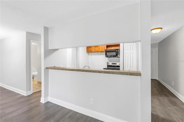 kitchen featuring stainless steel range with electric cooktop, a textured ceiling, and dark hardwood / wood-style flooring