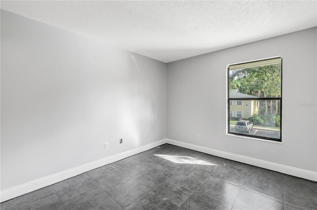 tiled empty room featuring a textured ceiling