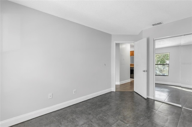 unfurnished bedroom with dark tile flooring and a textured ceiling