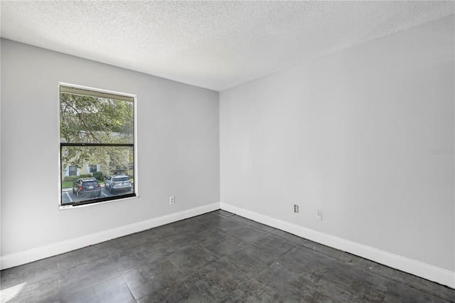 spare room with a textured ceiling and dark tile flooring