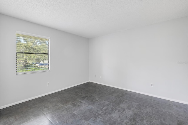 unfurnished room with dark tile floors and a textured ceiling