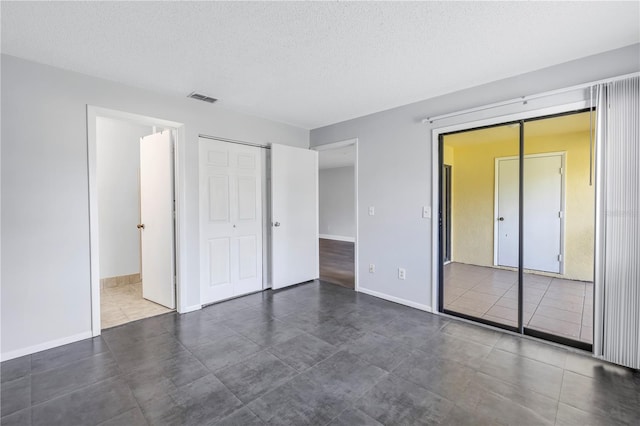 unfurnished bedroom featuring a closet, a textured ceiling, and dark hardwood / wood-style flooring