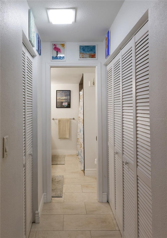 corridor with light tile floors and a textured ceiling