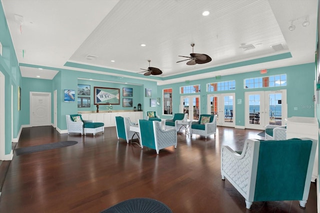 living room with french doors, a tray ceiling, dark hardwood / wood-style floors, and ceiling fan