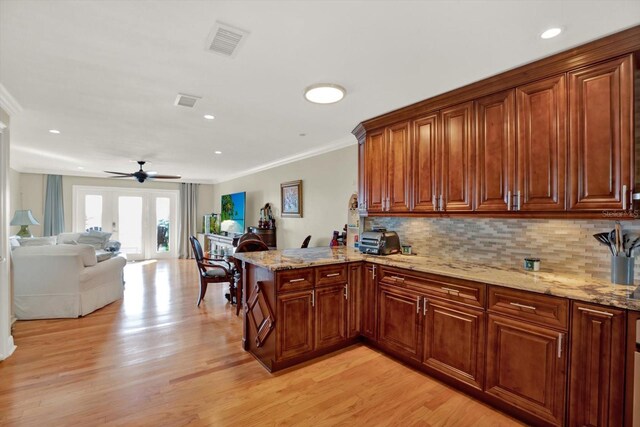 kitchen with kitchen peninsula, ceiling fan, crown molding, and light wood-type flooring