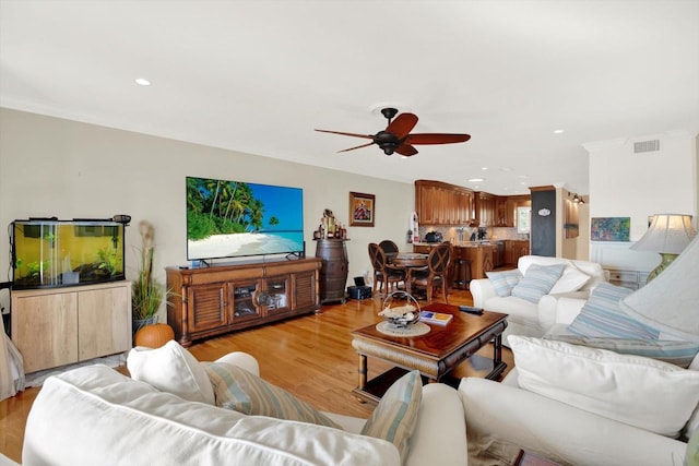 living room featuring light wood-type flooring, ceiling fan, and ornamental molding