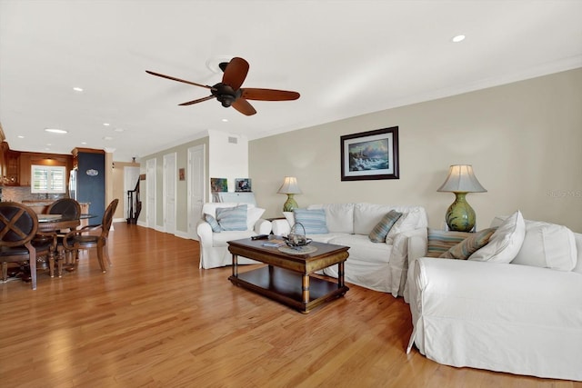 living room featuring ceiling fan, light hardwood / wood-style floors, and crown molding