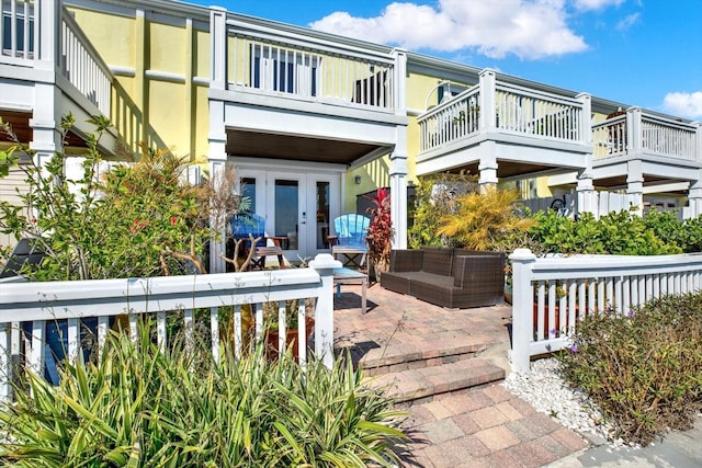 rear view of property with outdoor lounge area, a patio area, a balcony, and french doors