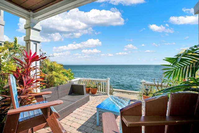 balcony with a water view, an outdoor hangout area, and a view of the beach