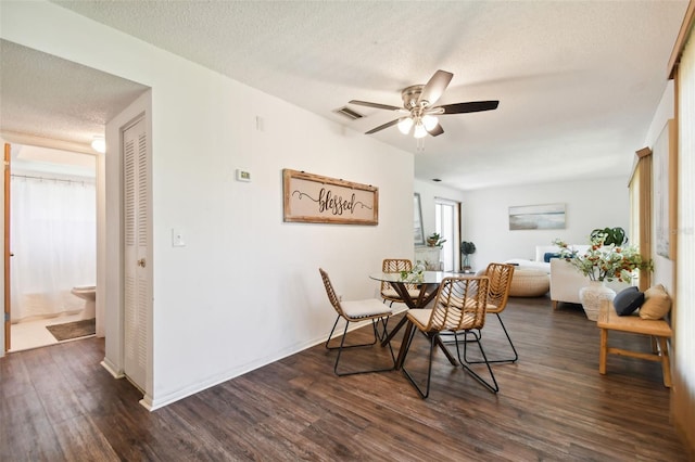 dining area with ceiling fan, dark wood-type flooring, and a textured ceiling