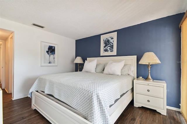 bedroom featuring a textured ceiling and dark hardwood / wood-style floors