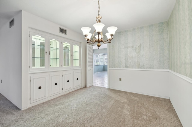 unfurnished dining area featuring light carpet and a notable chandelier