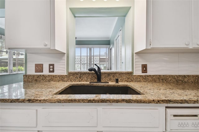 kitchen with white cabinetry, light stone counters, sink, and a wealth of natural light